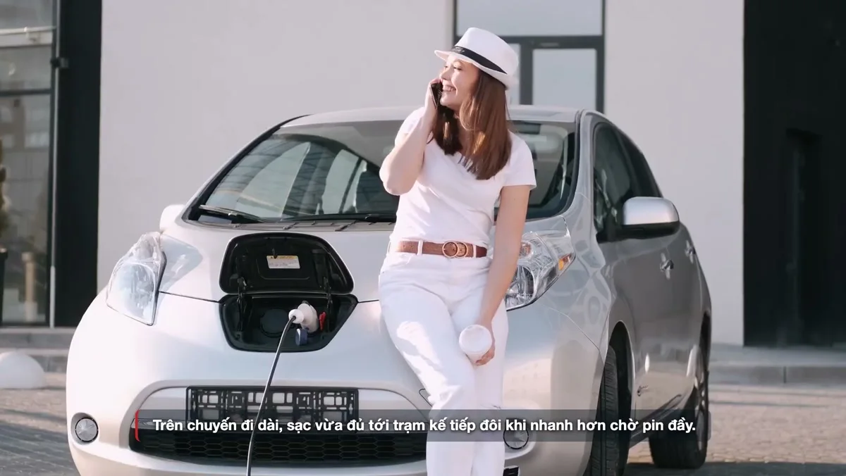 Người phụ nữ nghe điện thoại, đứng tựa vào xe điện đang cắm sạc ở đầu xe. Ảnh: khung hình từ video TC Motion
